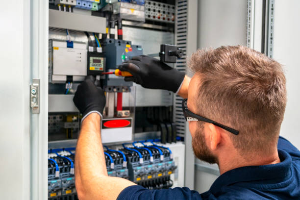 Technicien industriel en dépannage dans une armoire électrique.