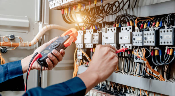 Technicien électricien industriel mesurant une tension dans une armoire électrique.