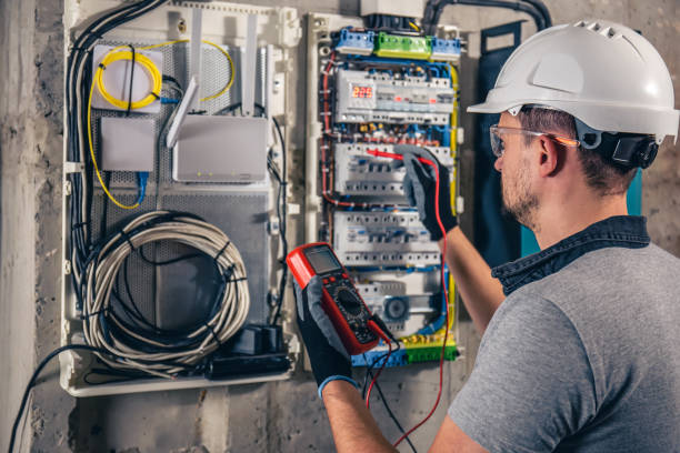 Technicien en réseau et automatisme travaillant dans une armoire électrique.